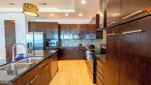 A modern kitchen with dark wooden cabinets, stainless steel appliances, and a granite countertop. - Dolphin Paradise  (South Padre Island)