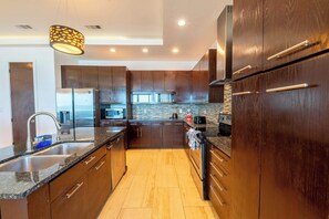 A modern kitchen with dark wooden cabinets, stainless steel appliances, and a granite countertop.