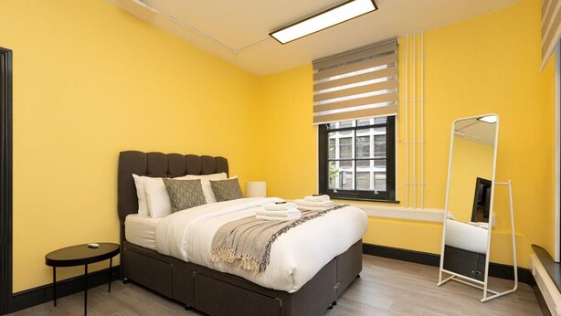 A modern bedroom with a bed, bedside table, and a window with blinds. - 1 Bed-sleeps 4-aircon-city Centre (London)