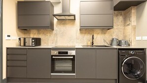 A modern kitchen with grey cabinetry, a built-in oven, a washing machine, and a microwave. - 1 Bed-sleeps 4-aircon-city Centre (London)