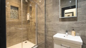 A modern bathroom with a glass-enclosed shower, a white vanity with a mirror, and a tiled floor. - 1 Bed-sleeps 4-aircon-city Centre (London)