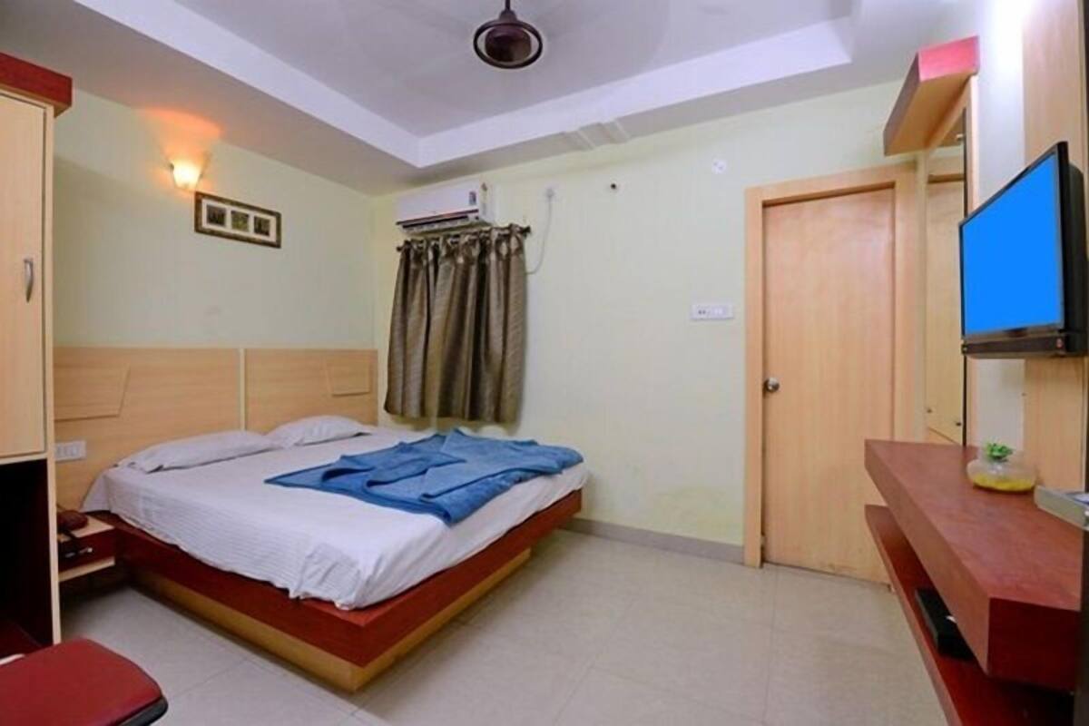 Un dormitorio con cama, escritorio, televisor y ventilador de techo.