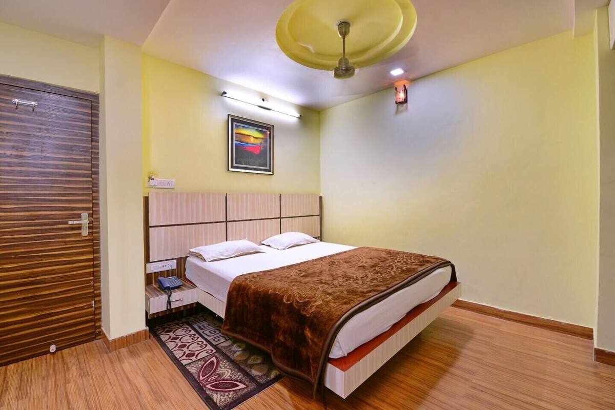 Un dormitorio con cama, teléfono de noche, luz empotrada en la pared y ventilador de techo.