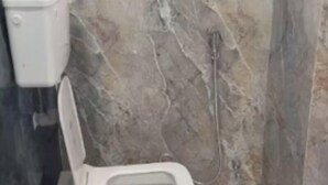 Kylpyhuone, jossa on wc, marmoriseinät ja näkyvissä oleva putkisto.