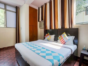 A hotel room with a large bed, a wooden wardrobe, and a window with curtains. - Hotel Perfect Inn (New Delhi)
