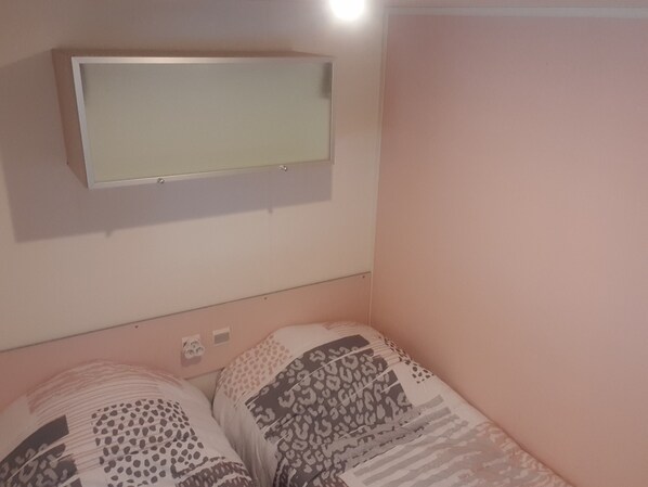 A bedroom with a bed, a wall-mounted TV, and a power outlet.