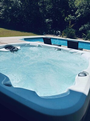 Ein Whirlpool mit Schwimmbad im Hintergrund.