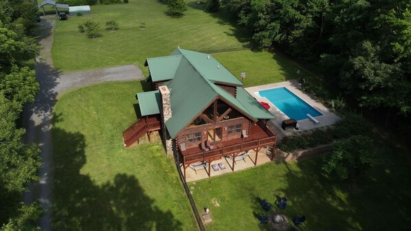 Eine große, rustikale Holzhütte mit einem grünen Dach, einem Schwimmbad und einer Terrassenfläche.