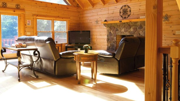 A log cabin interior with a stone fireplace, leather recliners, a television, and a dining table. - A Slice of Salisbury-Pool, Hottub 10 Acre (Salisbury)