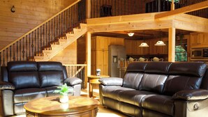 A wooden interior with a staircase, leather sofas, a wooden coffee table, and a kitchen area. - A Slice of Salisbury-Pool, Hottub 10 Acre (Salisbury)