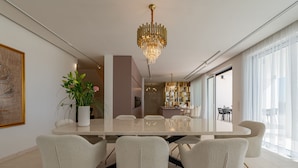 Une salle à manger moderne avec une grande table, des chaises blanches et un lustre.