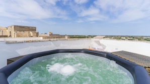 Ein Whirlpool mit Blick auf einen Wasserweg und Gebäude im Hintergrund.