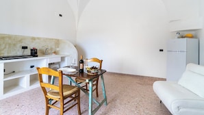 Eine kleine Küche mit Esstisch, Stühlen, einem Kühlschrank und einer Couch.