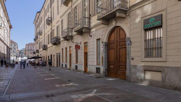 A cobblestone street lined with historic buildings, a café, and a visible 'Express' sign. - Casa Savoia by Wonderful Italy (Turin)
