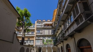 A courtyard with a central archway, surrounded by multi-story buildings with balconies and windows. - Casa Savoia by Wonderful Italy (Turin)