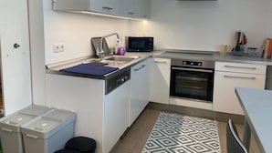 Una cucina compatta con mobili bianchi, un forno a microonde, un forno e un lavello.