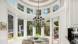 A dining area with a round table, chairs, and a chandelier.