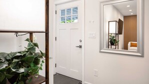 A hallway with a white door, a large mirror, and a potted plant.