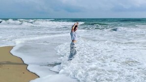 Eine Person steht am Strand, während Wellen an das Ufer schlagen.