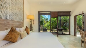 Ein Schlafzimmer mit einem großen Bett, einer Wandleuchte und Blick auf eine Terrasse mit Sitzgelegenheiten.