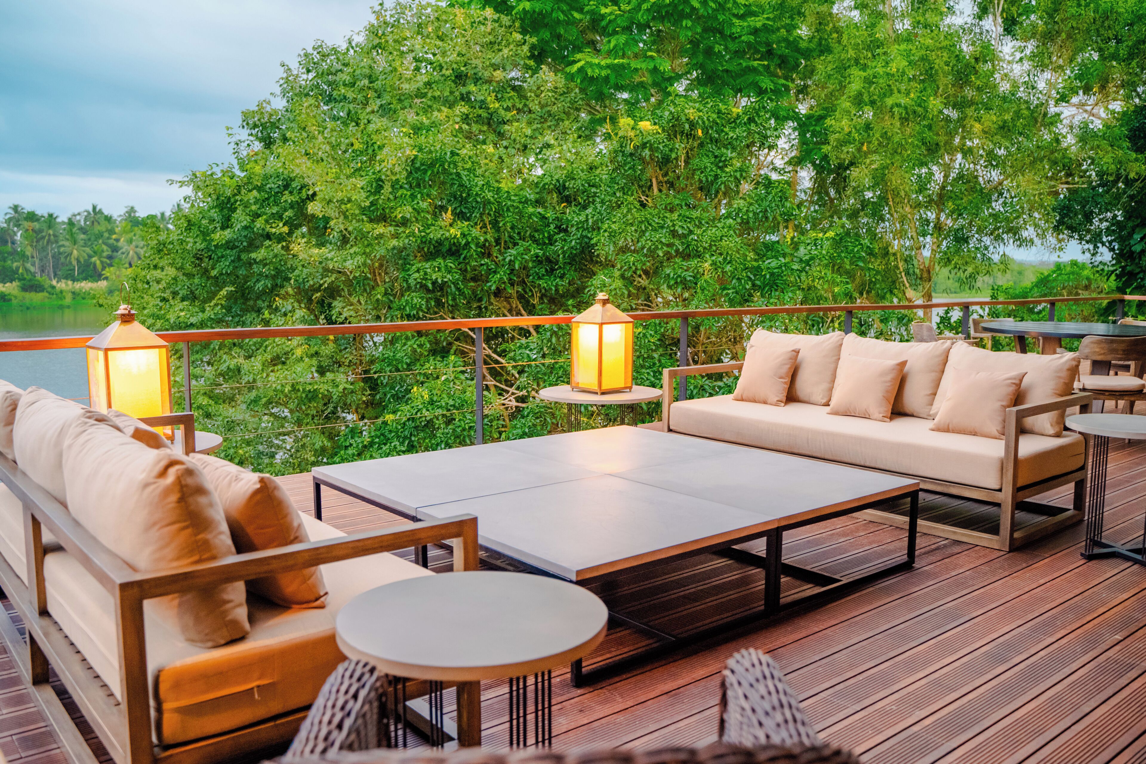 A deck with a sofa, two round tables, and two floor lamps.