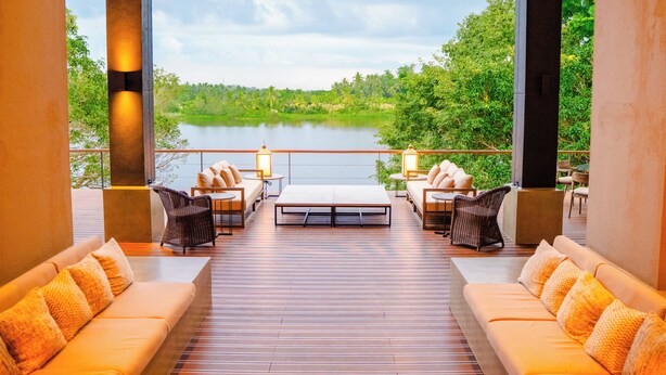 Un vaste espace extérieur aménagé avec une terrasse en bois, deux canapés avec des coussins et une table basse centrale.