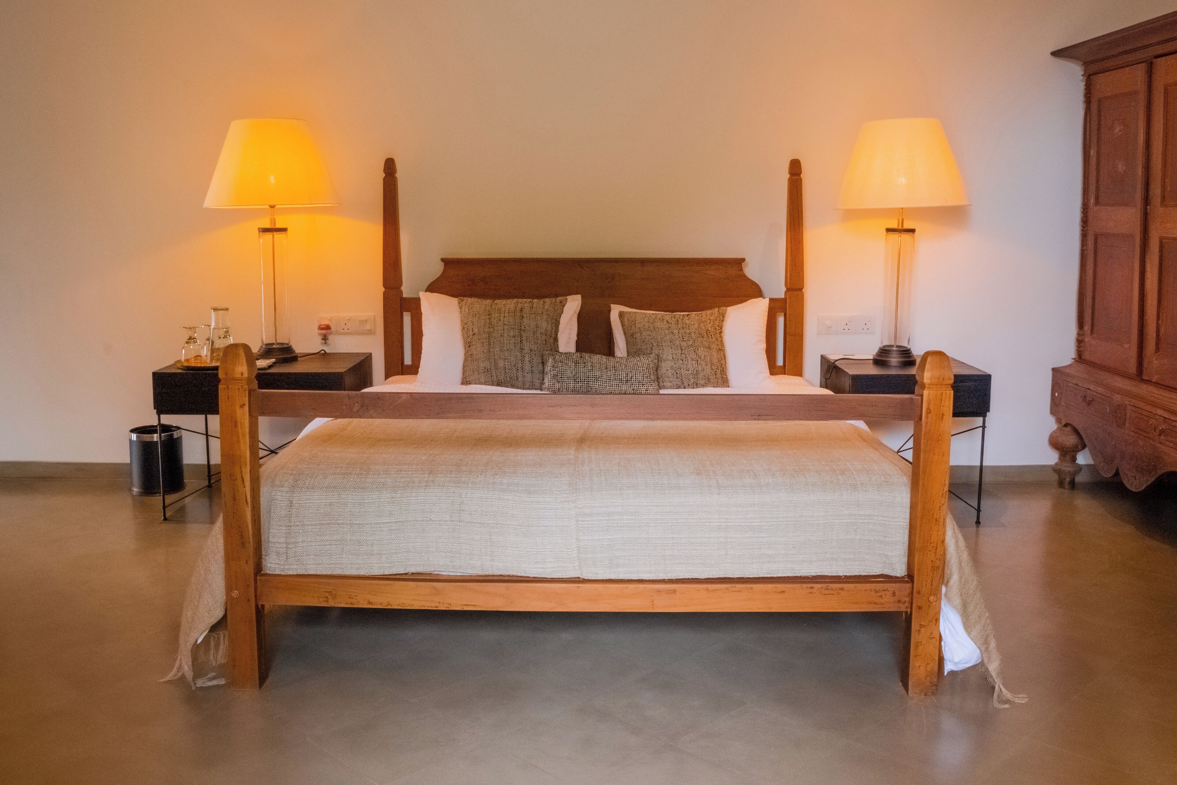 Una cama con dosel de madera, un cabecero, dos mesitas de noche y dos lámparas.