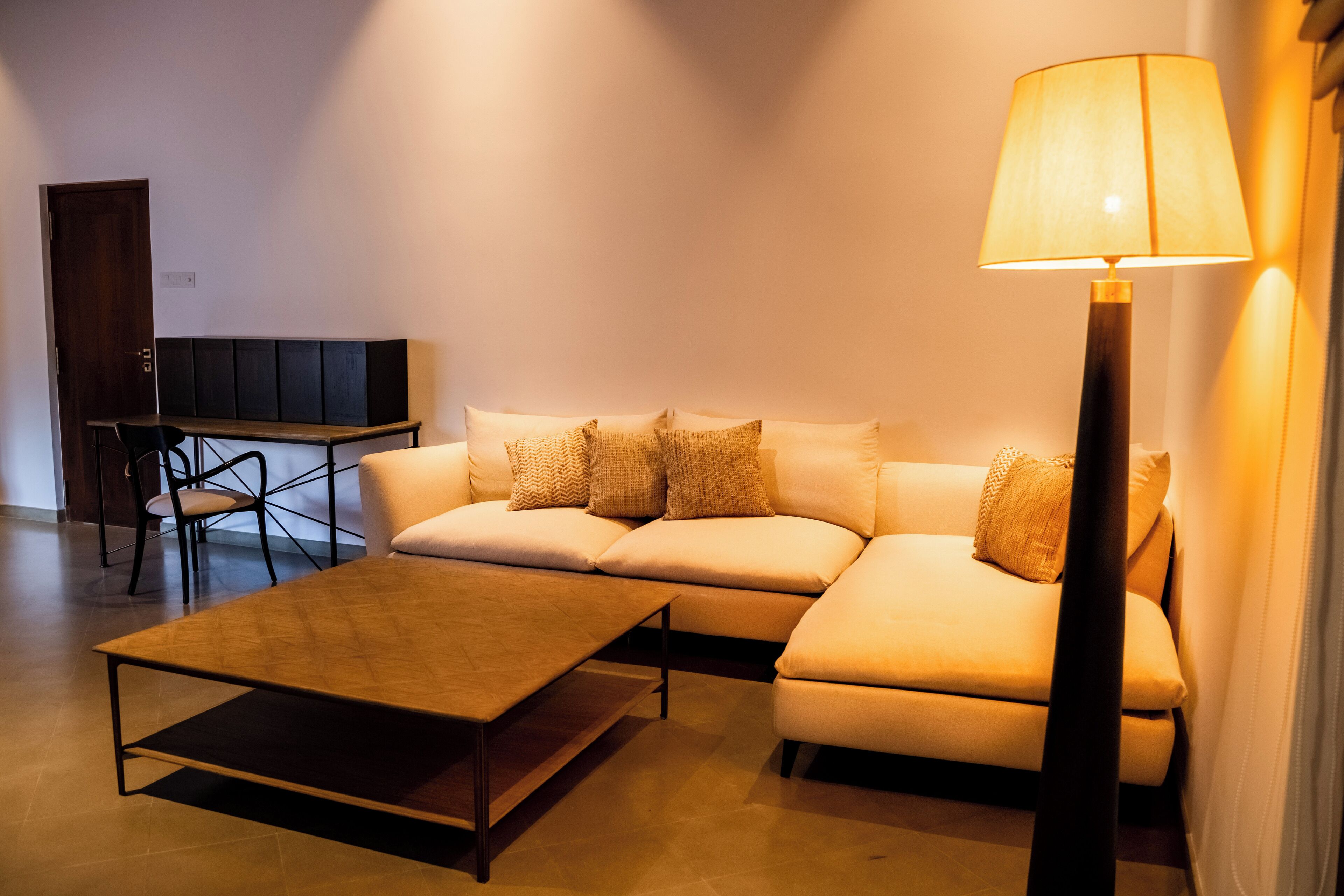 En moderne stue med sofa, sofabord, gulvlampe og TV-møbel.