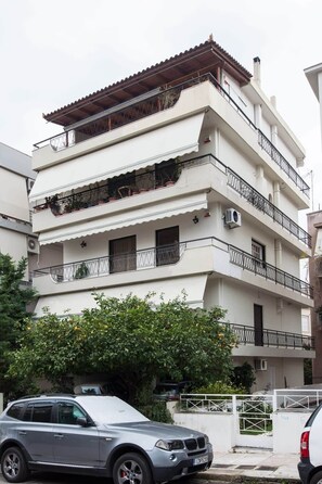 A multi-story residential building with balconies, air conditioning units, and a car parked in front. - Faliro Escape Modern Living (Paleo Faliro)