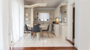 Una cucina moderna con mobili bianchi, un'area pranzo con tavolo e sedie rotonde, e una scala che conduce a un altro piano.