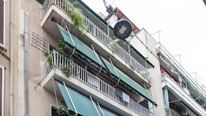 A multi-story building with balconies, a satellite dish, and a parked car.