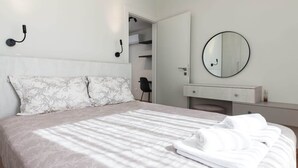 A bedroom with a bed, a bedside table, a mirror, and a wardrobe.