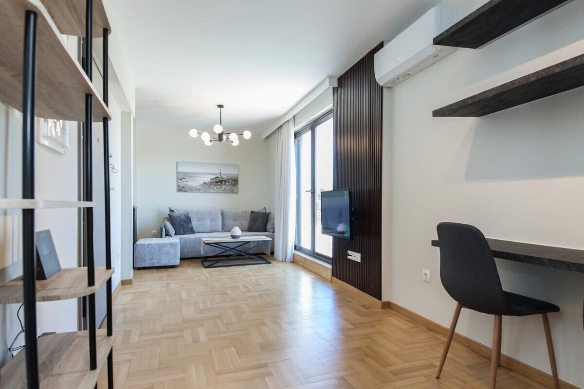 Un soggiorno moderno con un divano, televisione e una zona pranzo con una sedia.