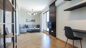 A modern living room with a sofa, television, and a dining area with a chair.
