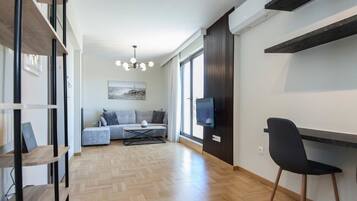 Un soggiorno moderno con un divano, televisione e una zona pranzo con una sedia.