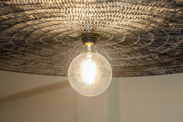 A hanging light fixture with a woven, circular design.