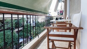 Een balkon met houten stoelen en een tafel, met uitzicht op een tuin met weelderige begroeiing.
