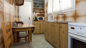 Een kleine keuken met houten kastjes, een magnetron en een Bosch oven.