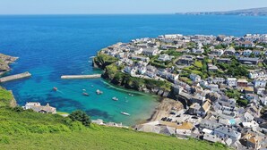 A coastal town with a dense cluster of buildings, a clear blue sea, and boats near the shore.