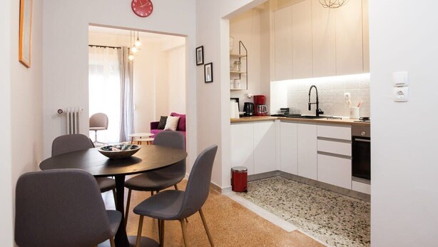 A compact kitchen with white cabinets, a coffee machine, and a red trash bin. - Sleek & Modern Apartment Near Metaxourgeio (Athens)