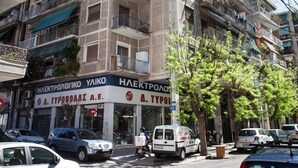 A multi-story building with balconies, a storefront, and parked cars. - Sleek & Modern Apartment Near Metaxourgeio (Athens)