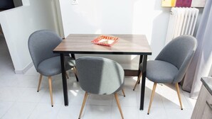 A dining area with a wooden table and two grey chairs with wooden legs. - Modern apt in heart of Paleo Faliro! (Athens)