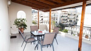 A balcony with a table and chairs, a potted plant, and a view of residential buildings. - Modern apt in heart of Paleo Faliro! (Athens)