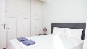 A hotel room with a bed, a wardrobe, and a nightstand. - Modern apt in heart of Paleo Faliro! (Athens)
