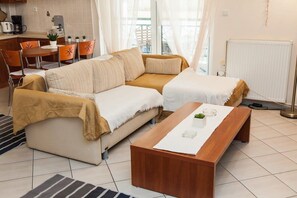 Een moderne woonkamer met een bank, een salontafel, en een eethoek met stoelen en een tafel.