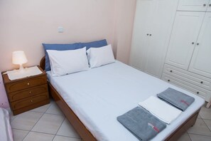 A bedroom with a bed, a nightstand, a lamp, and a wardrobe. - Cozy modern apt in Peristeri (Athens)