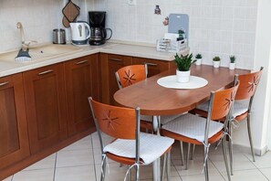Een kleine keuken met een houten tafel en stoelen, een koffiezetapparaat en een waterkoker.