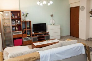 A living room with a sofa, TV, wooden entertainment unit, and a white cabinet. - Cozy modern apt in Peristeri (Athens)