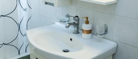Une salle de bain avec un lavabo blanc, un miroir au-dessus, et un rideau de douche à motifs noirs et blancs.