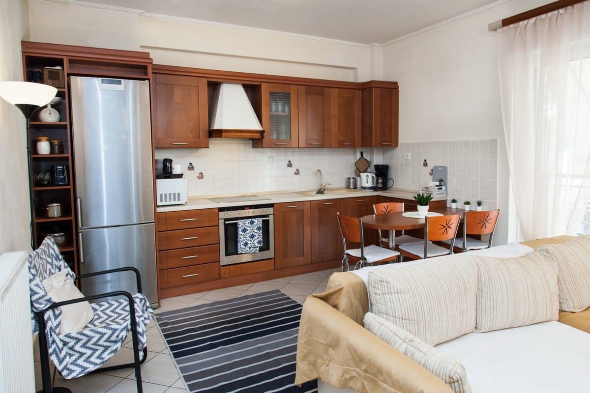 Una cocina moderna con armarios de madera, un refrigerador de acero inoxidable y un comedor con mesa y sillas.